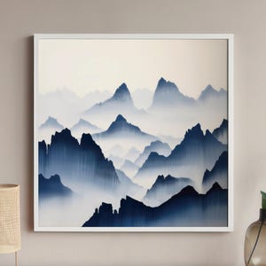 May include: A framed abstract painting of a mountain range with blue and white hues. The mountains are obscured by fog or clouds, creating a sense of depth and mystery.