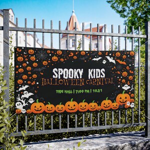 May include: A black Halloween banner with orange pumpkins, bats, and ghosts. The banner reads "Spooky Kids Halloween Carnival" with the time and date. The banner is hanging on a metal fence.
