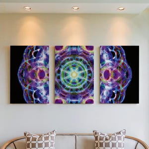 May include: Triptych wall art featuring abstract, colorful designs. The artwork is composed of three rectangular panels. The central panel displays a circular, mandala-like pattern with green, yellow, and blue hues. The side panels have similar designs with purple and blue colors.