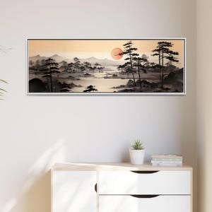 以下が含まれることがあります： 日本の水墨画風の額入り風景画。夕日を背景に、山、木々、湖のある静かな風景を描いています。色使いは主に黒、白、オレンジです。