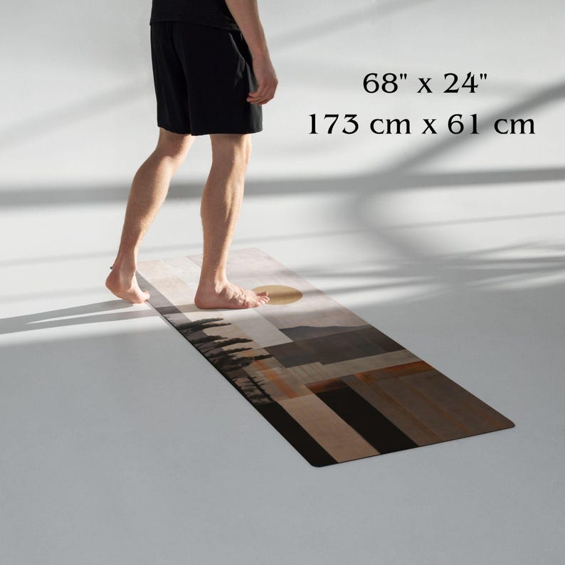 May include: A rectangular yoga mat with a landscape design. The mat is 68 inches long and 24 inches wide. The design features a sun, trees, and geometric shapes in shades of brown, beige, and black.