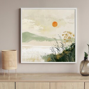 May include: A white framed print of a minimalist landscape painting with a large orange sun, green hills, and tall grass in the foreground.