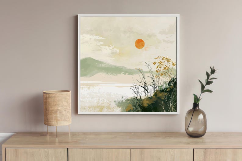 May include: A white framed print of a minimalist landscape painting with a large orange sun, green hills, and tall grass in the foreground.