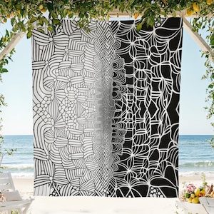 Puede incluir: Una toalla de playa con estampado en blanco y negro con un diseño geométrico. La toalla está colgada de una estructura de madera con una playa y el océano de fondo. El diseño hace la transición de blanco a negro.