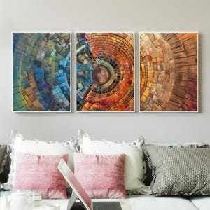May include: A triptych of abstract art prints. Each framed artwork features a circular design with a mosaic-like appearance. The color palettes range from cool blues and greens to warm oranges and browns, creating a visually dynamic display.