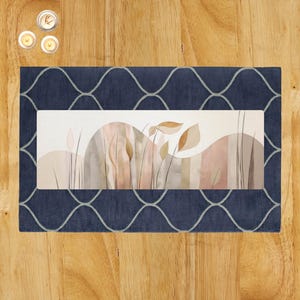 May include: A rectangular rug with a navy blue border featuring a light gray geometric pattern. The center of the rug displays a watercolor landscape with beige, pink, and brown tones, depicting hills and foliage.