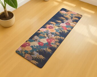 May include: A rectangular yoga mat with a dark blue background and a floral design. The floral pattern includes pink, red, orange, and yellow flowers with gold accents. The mat is on a light wood floor.