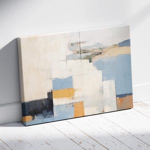 Könnte beinhalten: Abstrakte Leinwandkunst mit einem geometrischen Design. Das Kunstwerk verwendet Blöcke in Weiß, Blau, Gelb und Schwarz. Die Leinwand lehnt an einer weißen Wand und einem weißen Holzboden.