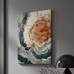 May include: Abstract canvas art featuring a cross-section of a tree trunk. The artwork displays concentric rings in shades of brown, beige, and teal, creating a natural, organic pattern. The canvas is rectangular and mounted on a wall.