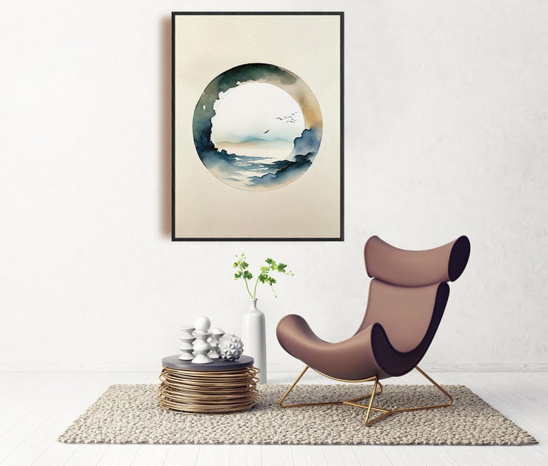 May include: A framed watercolor print featuring a circular landscape scene with a blue and green color palette. The artwork hangs above a modern brown chair with gold legs, a small side table, and a vase with greenery.