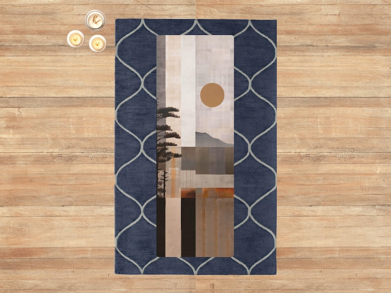 May include: A rectangular rug with a navy blue border featuring a light gray, geometric pattern. The center of the rug displays an abstract landscape painting with a sun, mountains, and trees. The rug is placed on a wooden floor.