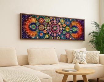 Puede incluir: Una obra de arte abstracta colorida enmarcada con un marco marrón oscuro. La obra presenta un patrón de círculos concéntricos en tonos de naranja, amarillo, verde, azul y morado. La pieza se exhibe sobre un sofá beige en un salón.