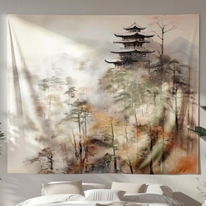 May include: A tapestry featuring a watercolor painting of a Japanese pagoda atop a misty mountain. The artwork uses muted tones of brown, green, and beige, creating a serene and naturalistic scene. The tapestry is rectangular and hangs above a bed.