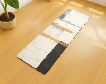 May include: Rectangular yoga mat with an abstract design. The mat features a white background with black, gray, and tan rectangular shapes. The mat is placed on a light wood floor.