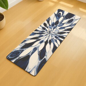 May include: A rectangular yoga mat featuring a blue and white floral pattern. The design, resembling a flower, radiates from the centre. The mat is placed on a light-coloured wooden floor.