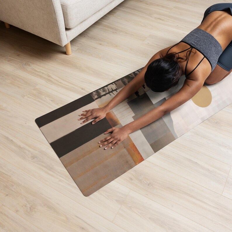 May include: A yoga mat with an abstract design in shades of brown, gray, and orange. The mat features a geometric pattern with a large gold circle and is used for stretching exercises.