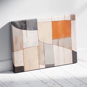 Könnte beinhalten: Abstrakte Leinwandkunst mit einem geometrischen Design in neutralen Tönen und einem orangefarbenen Quadrat. Das Kunstwerk lehnt an einer weißen Wand und einem weißen Holzboden. Das Stück hat eine moderne Ästhetik.