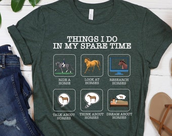 May include: Dark green t-shirt with the text "THINGS I DO IN MY SPARE TIME" and illustrations of horses. The shirt also features images of riding, looking at, and researching horses. A pair of blue jeans and brown sandals are also in the image.