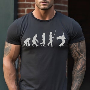 May include: A dark gray t-shirt with a white graphic of the evolution of man, ending with a man playing an electric guitar.