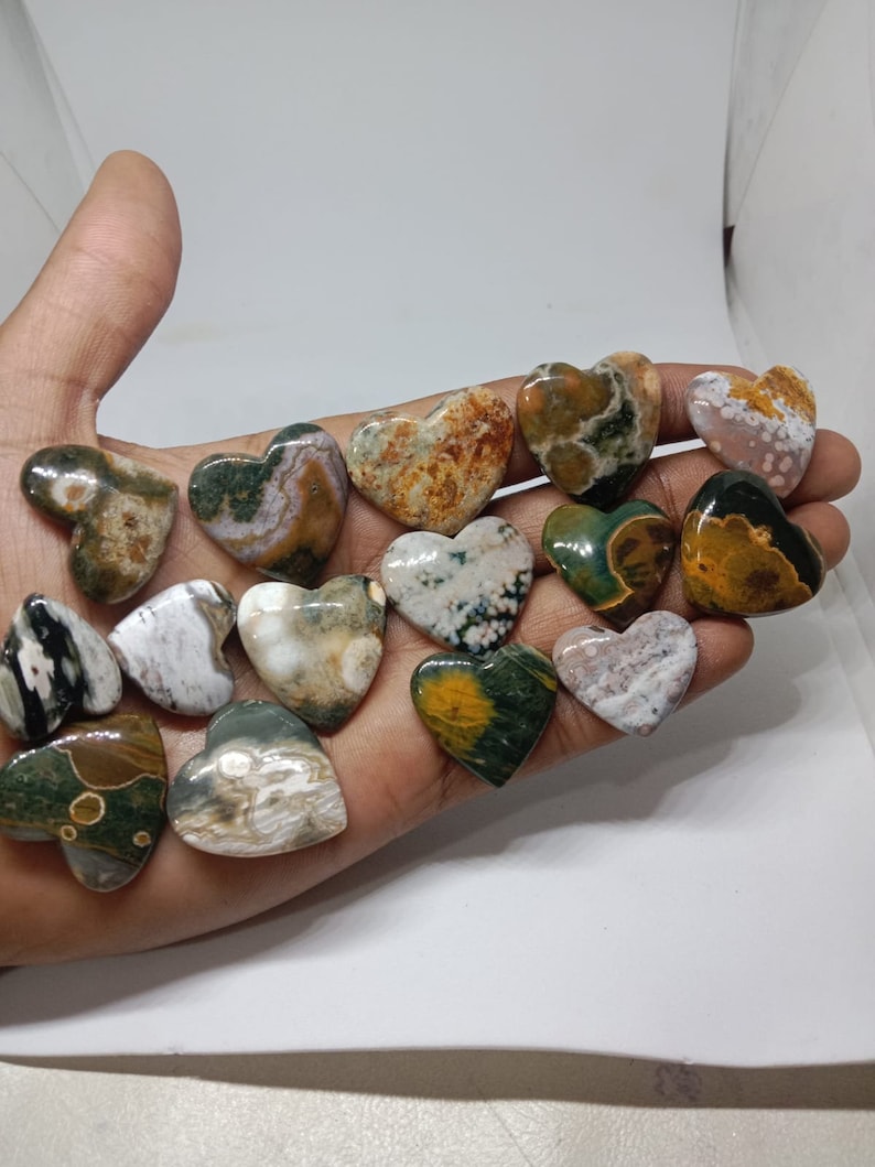 May include: A collection of 14 heart-shaped polished stones with various patterns of green, brown, white, and yellow.