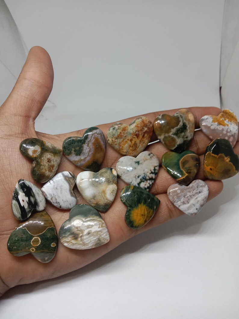 May include: A collection of 14 green, brown, and white heart-shaped polished stones. The stones have a unique marbled pattern.