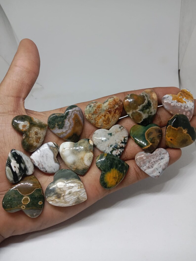 May include: A collection of 15 heart-shaped polished stones with a variety of green, brown, white, and yellow patterns.