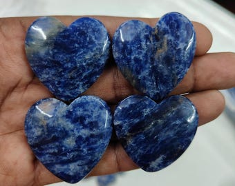 May include: Four polished heart-shaped stones. The stones are a deep blue color with white and gray marbling. The hearts are smooth and appear to be made of a natural stone material.