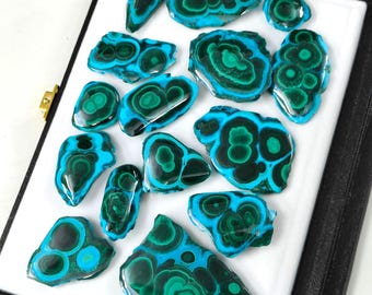May include: A collection of 15 polished malachite and azurite cabochons in various shapes and sizes. The cabochons are a vibrant green and blue with intricate patterns.