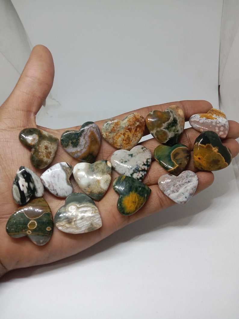 May include: A collection of 15 heart-shaped polished stones with a variety of green, brown, white, and yellow patterns.