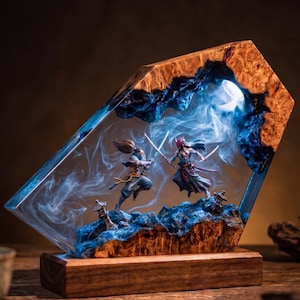 May include: A decorative lamp featuring a natural wood frame enclosing a blue resin center. Inside the resin, two miniature figures with swords are engaged in combat amidst swirling white smoke effects, illuminated by a bright internal light source.