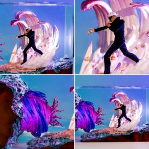 May include: A composite image featuring a figure in a black suit and white blindfold, posed in front of a stylized wave. The wave is white with pink and purple accents, set against a blue background. The scene is enclosed in a clear, rectangular container.