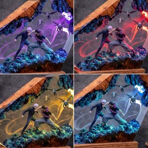May include: A diorama featuring two anime figures in a combat pose, set within a wooden frame filled with resin. The scene includes small winged creatures and swirling light effects in purple, red, yellow, or white, set against a rocky base.