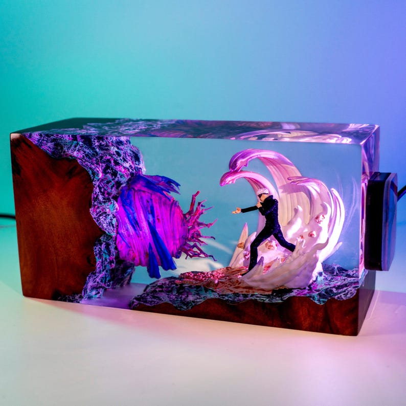 May include: A rectangular resin art piece featuring a miniature figure in a dynamic pose, set against a backdrop of stylized waves and abstract forms. The piece has a wooden base and a vibrant color palette of purple, blue, and white.