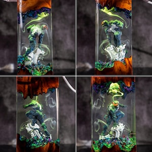 May include: Four images of a resin art piece featuring a superhero figure. The resin is clear, with a wooden base and colorful accents of green, blue, and purple. The superhero is in a dynamic pose, with a white base. The piece is encased in a rectangular shape.