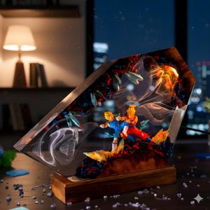 Op de afbeelding: Een decoratieve lamp met twee anime-figuren in een dynamische vechthouding, ingesloten in een helder harsblok met wervelende witte rookeffecten, donkere rotsachtige texturen en oranje accenten, gemonteerd op een rechthoekige houten voet.