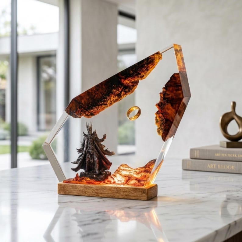May include: A decorative display piece featuring a dark armored figure standing on a textured amber-colored base, with a gold-toned ring suspended in the center of a clear resin frame containing jagged, dark wood-like elements.