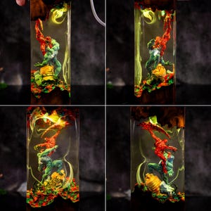 May include: A rectangular resin art piece featuring two superhero figures in a dynamic pose, encased in a clear resin block. The figures are red and green, set against a backdrop of colorful, swirling resin and wood grain.