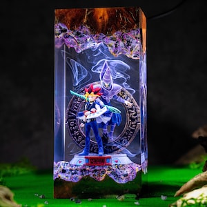 May include: A rectangular resin lamp featuring a Yu-Gi-Oh! character with spiky hair and a Dark Magician figure standing before a circular stone-like emblem. The base displays the number 4000 in red, surrounded by purple and amber resin textures.