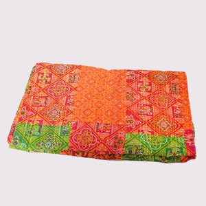 May include: A folded, patterned textile featuring a patchwork design. The quilt showcases a vibrant color palette of red, orange, and green. Geometric and paisley motifs are visible throughout the fabric, creating a visually rich and textured appearance.