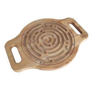 Pode incluir: Quebra-cabeça de labirinto de madeira com uma capa de plástico transparente. O labirinto circular apresenta caminhos concêntricos. A base de madeira castanho-claro tem duas pegas. O quebra-cabeça foi concebido para entretenimento e desenvolvimento de habilidades, cerca de 30 cm de diâmetro.