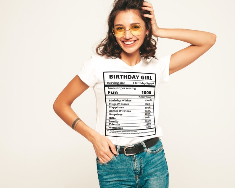 May include: White t-shirt with a black graphic of a nutrition label that reads "Birthday Girl" and lists the amount of "Fun" per serving as 1000. The label includes items like "Birthday Wishes", "Hugs & Kisses", "Happiness", "Games & Prizes", "Surprises", "Gifts", "Family", "Friends", and "Memories".