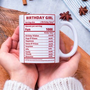 May include: White ceramic mug with a red and white design that says "Birthday Girl" and lists the "Daily Value" of fun things like birthday wishes, hugs and kisses, happiness, games and prizes, surprises, gifts, family, friends, and memories.