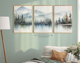 May include: Three watercolor paintings of a misty mountain lake scene with trees and reflections in the water. The paintings are framed in wood and hung on a light green wall.