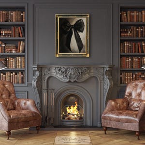 May include: A black and white bow art print in a gold frame hangs above a fireplace with a burning fire. Two brown leather armchairs flank the fireplace, and bookshelves filled with books are on either side.