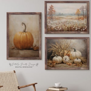 May include: Set of three fall-themed printable art prints. The first print features a single orange pumpkin on a brown background. The second print shows a field of white wildflowers with a forest in the background. The third print features a group of white pumpkins with wheat stalks and fall leaves.