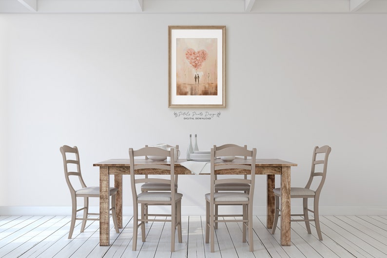 May include: A digital download of a watercolour painting depicting a couple standing under a heart-shaped balloon made of pink flowers. The painting is framed and hanging on a white wall above a wooden dining table with chairs.