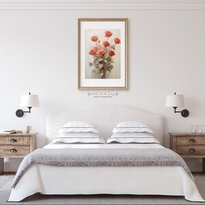 May include: A white bed with a gray blanket and two white pillows with black stripes. There are two wooden nightstands with lamps on either side of the bed. A framed print of a bouquet of red roses is hanging on the wall above the headboard.