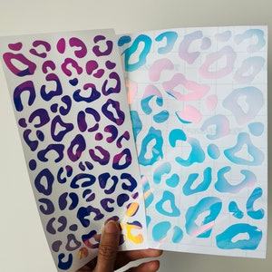 May include: Two sheets of iridescent leopard print vinyl. One sheet is pink and blue, the other is purple and blue.