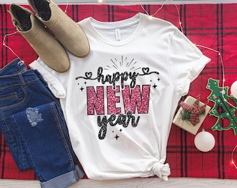May include: White t-shirt with a black and pink glitter design that says "happy new year".