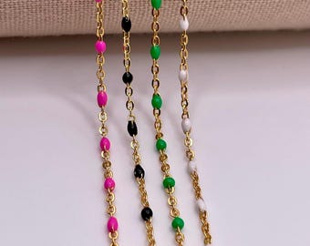 May include: Four gold chains with different colored beads. The chains have pink, black, green, and white beads.